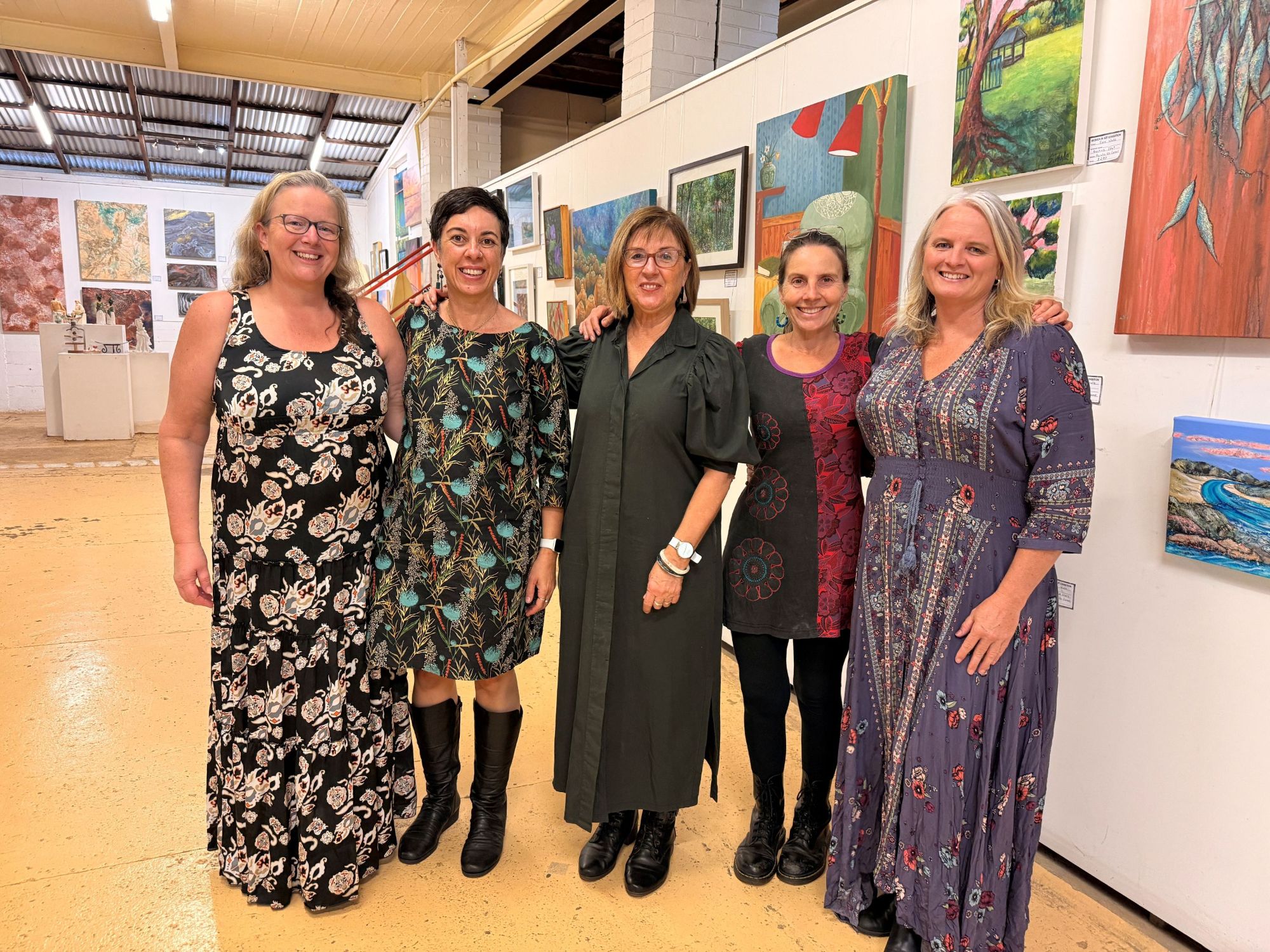 five women standing in front of art works